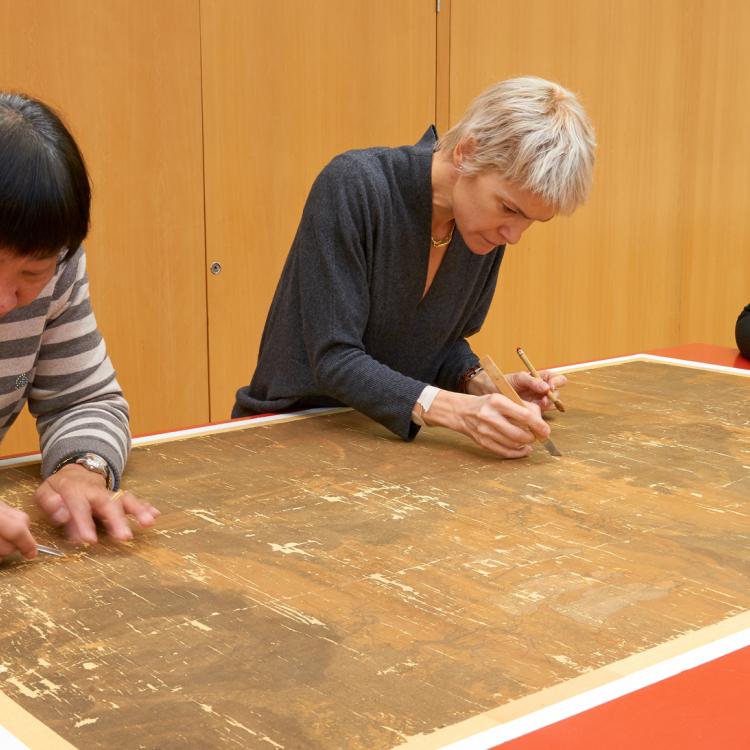 Three conservators working on a silk painting. 