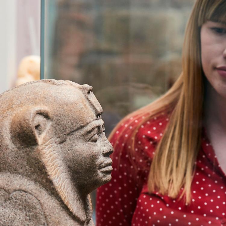 A visitor looking at the granite sculpture of the Sphinx of King Taharqo