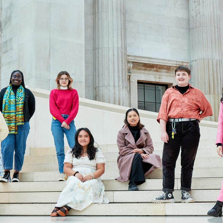 Seven members of the British Museum's Youth Collective for 2021 sitting on the steps of the Museum's Great Court.