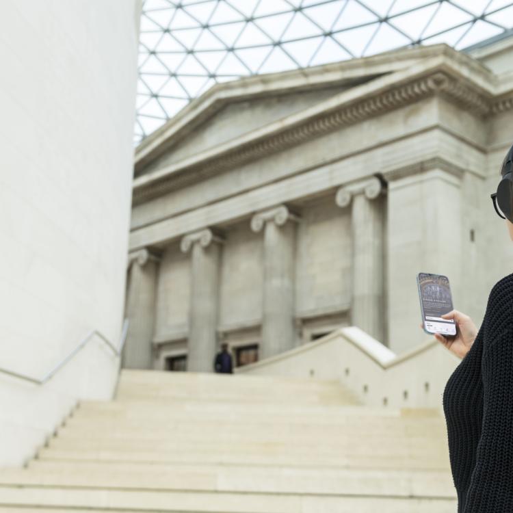 Woman with headphones on using the British Museum Audio app.