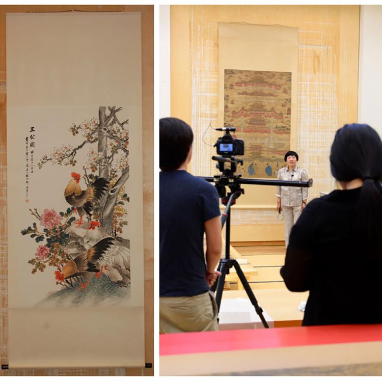 Jin Xian Qiu is interviewed whilst standing in front of a Chinese scroll