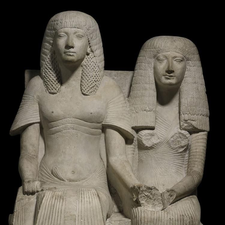 Statue of Horemheb and Amenia seated on chairs with lion-paw feet. Damage to chest and hands of Amenia.