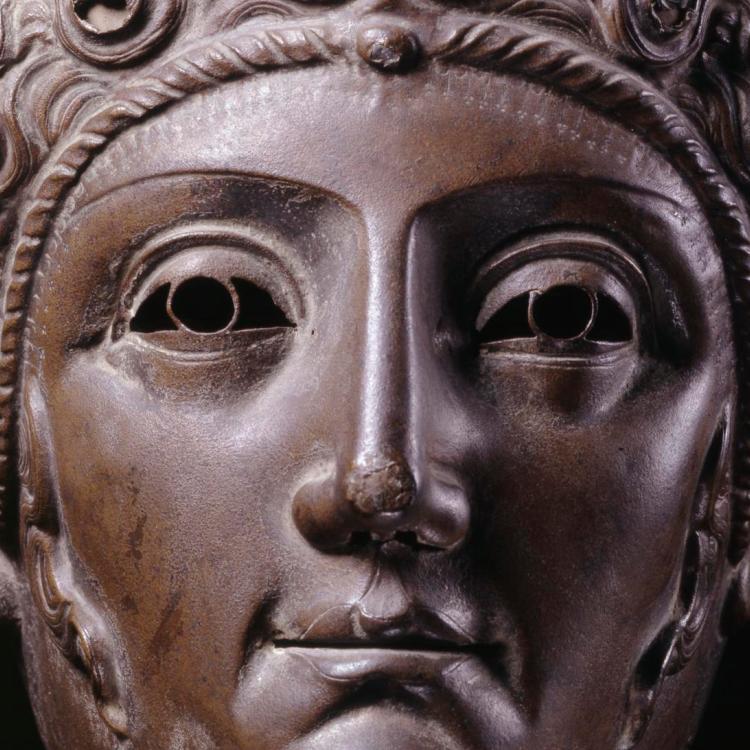 Close up of bronze parade mask of a woman's face