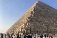 A group of tourists standing at the bottom of a pyramid in Egypt. 