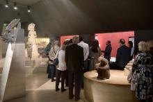 Group of people stood in the Mexico gallery between collection objects and large sculptures.