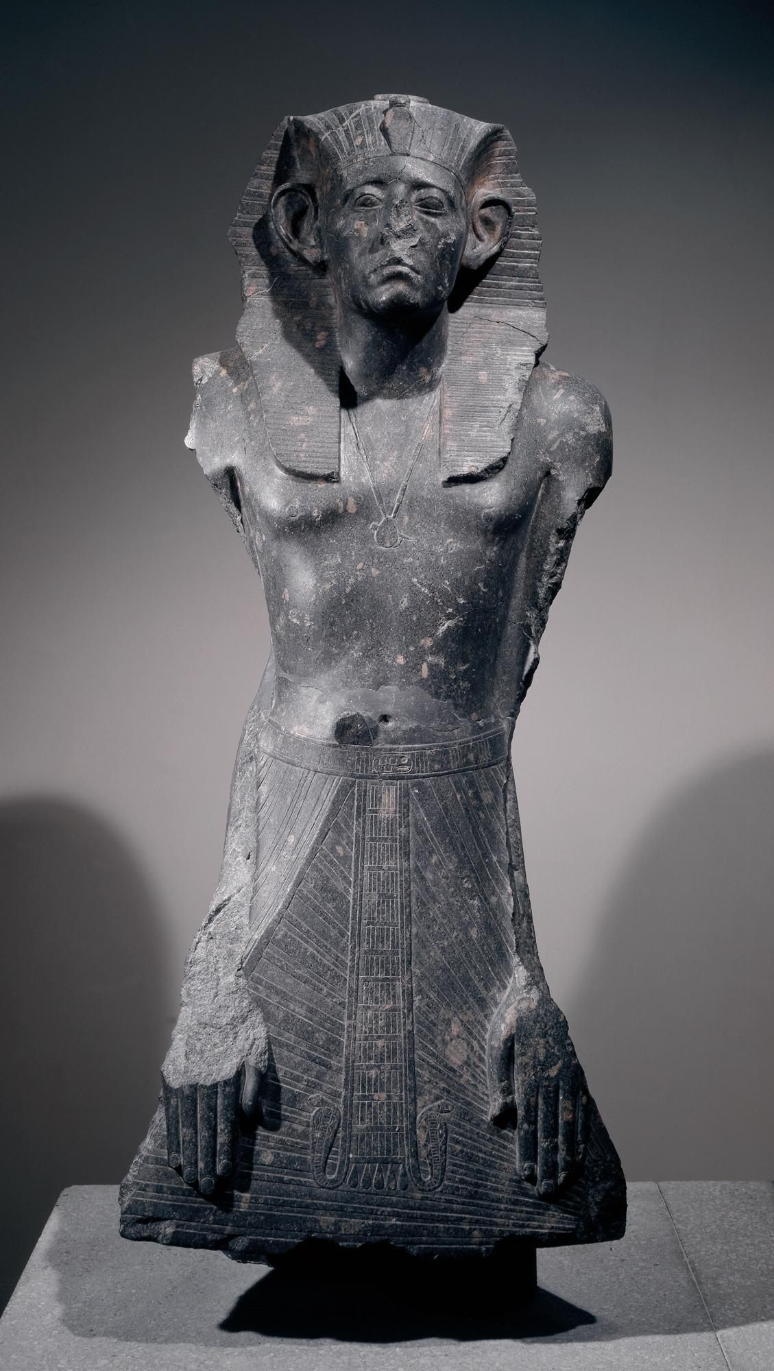 Granodiorite statue of Senusret III wearing nemes; prenomen on belt; legs and arms lost (hands still present on apron).