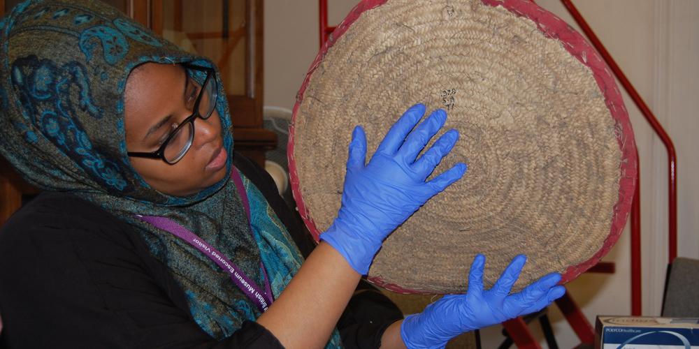 Woman examining food mat for display, Somali project, British Museum