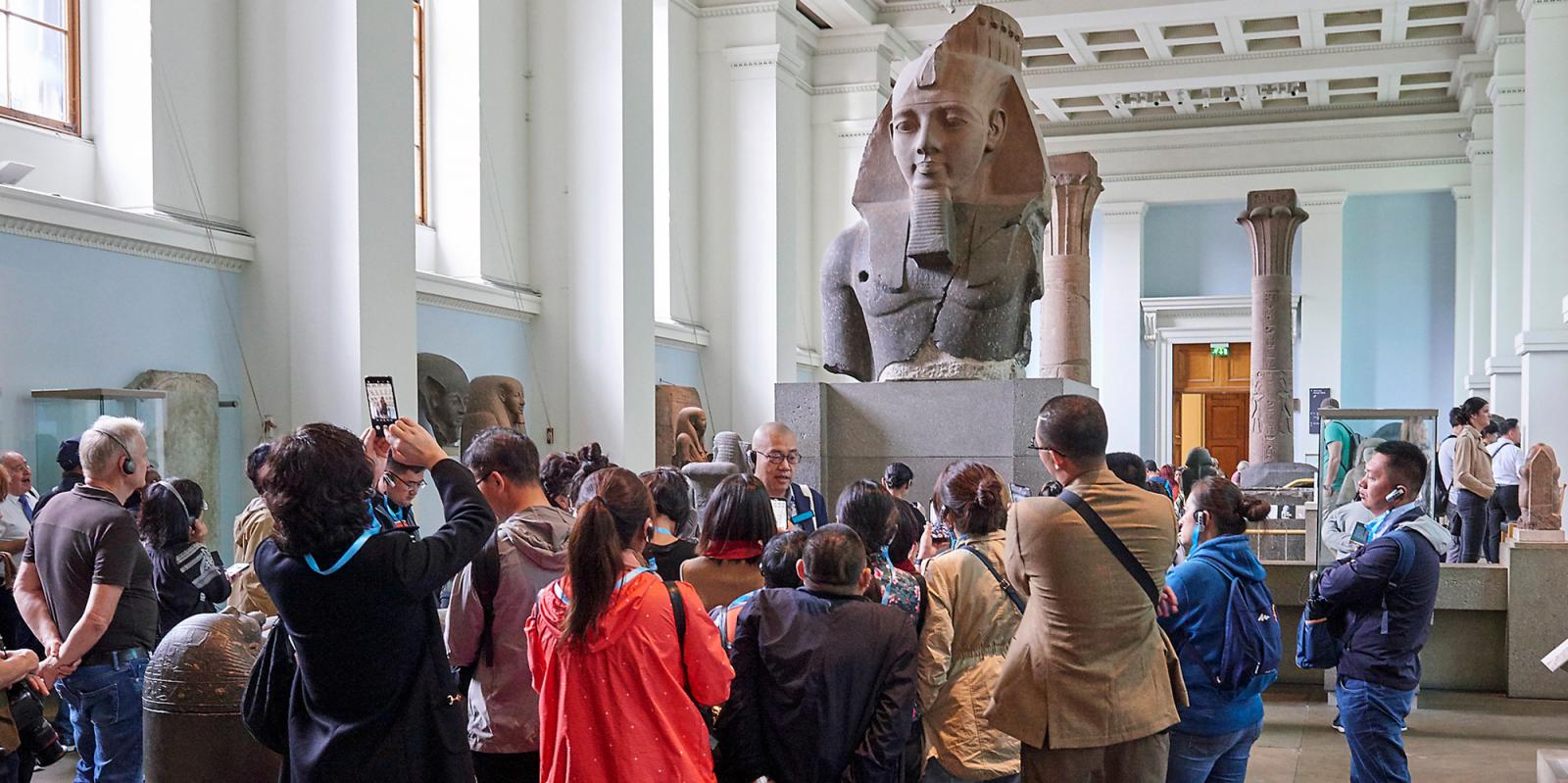 A large group of visitors having a tour in the Egyptian sculpture gallery