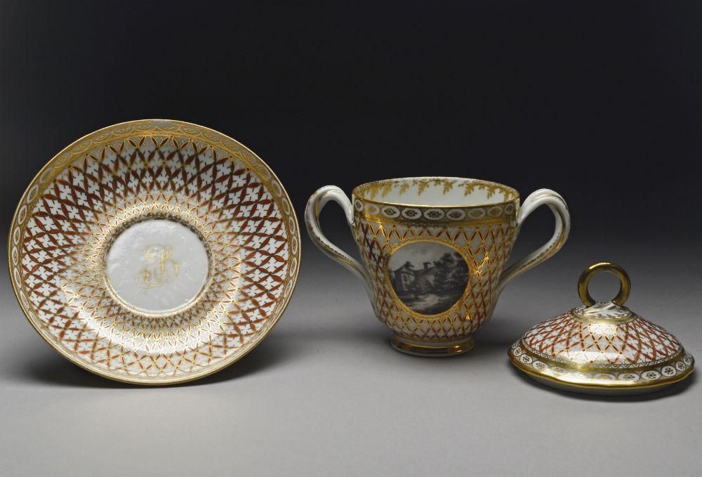 One of two patterned porcelain cups with lids and a saucer.