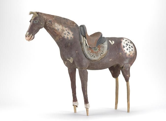 A figure of a brown horse with black spots and with a saddle. 