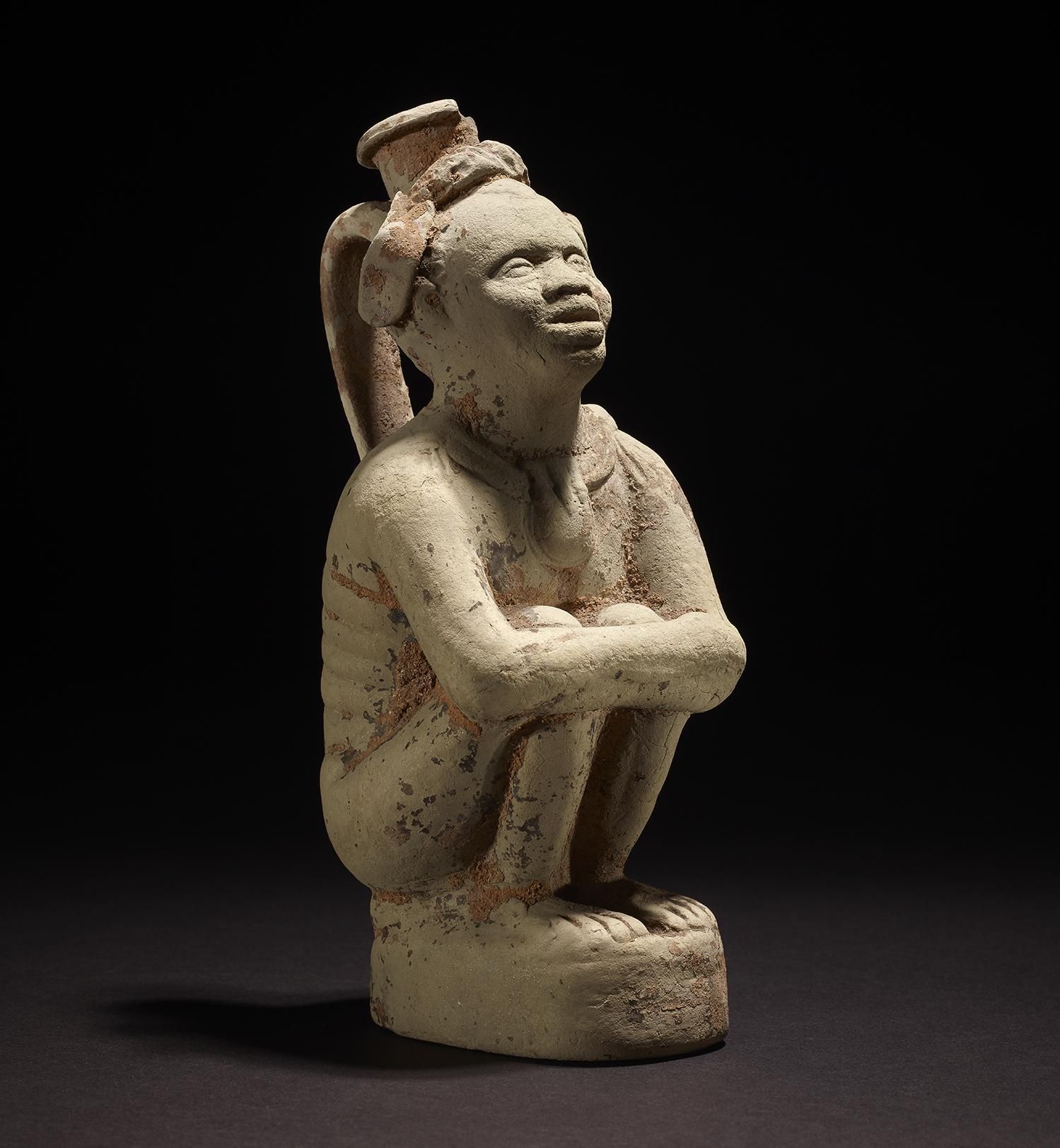 A handled pottery flask shaped as an enslaved crouching African male figure.