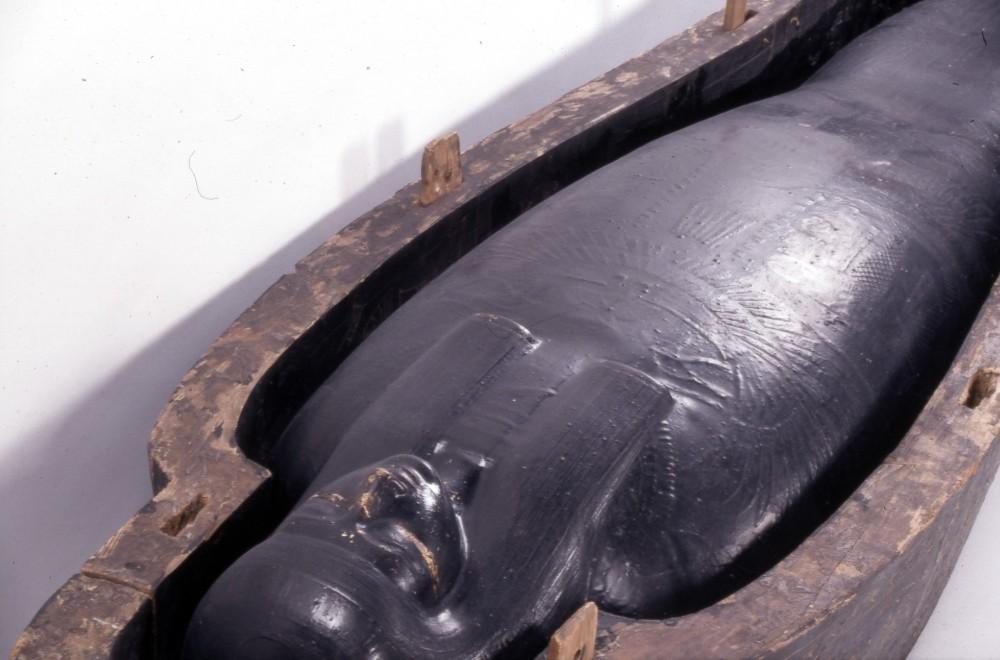 Close up of mummy in cartonnage and open wooden coffin