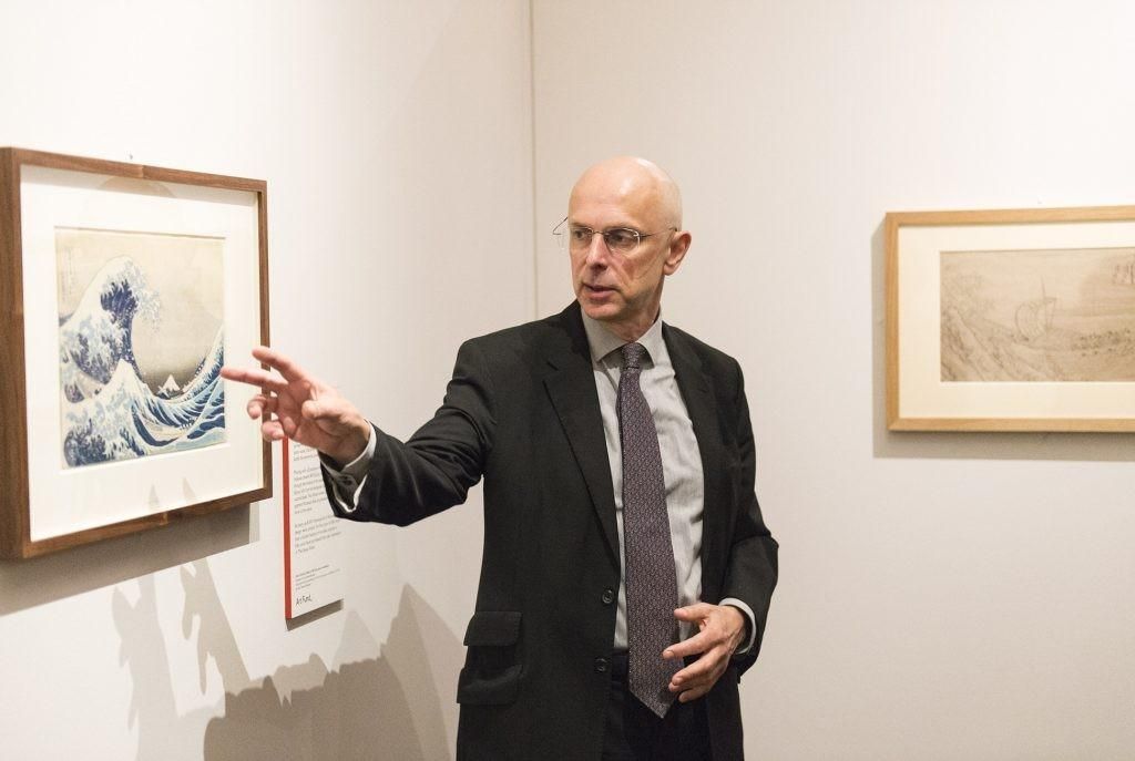 Tim Clark pointing at a framed Hokusai print