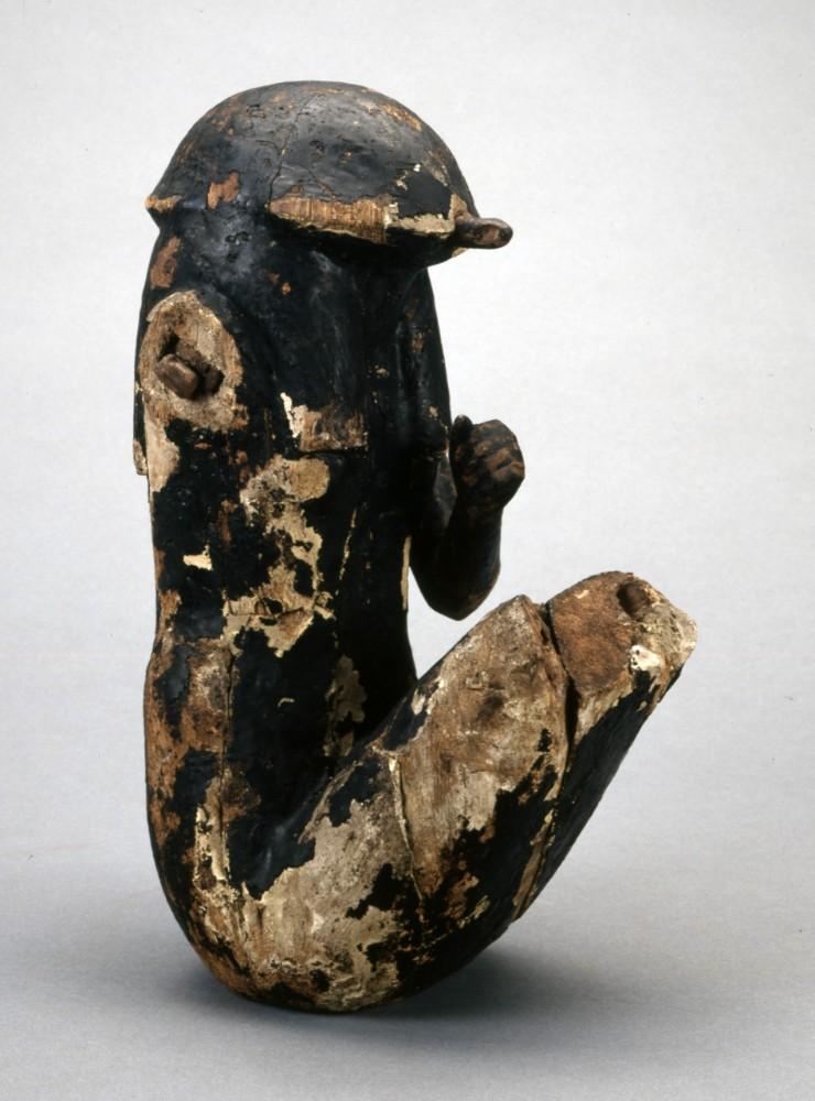 Seated figure with turtle head, covered in black resin