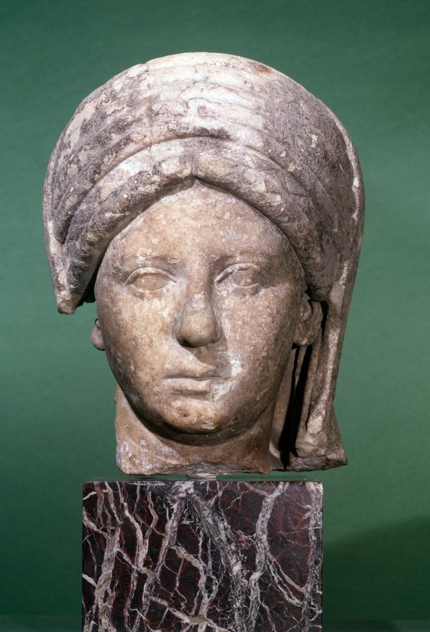 Marble head from a portrait statue of a veiled priestess of the goddess Vesta. The headdress identifies the subject as a Vestal Virgin. Above her hair are six folds of the infula, a long woollen band wrapped about the head to hang in two loops, passed behind the ears