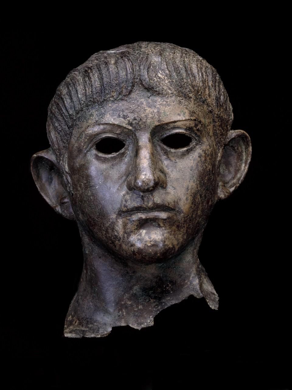 Copper alloy head of the emperor Nero from a life-size statue. The face is heart-shaped, with a strong chin and nose, large, slightly slanting eyes and prominent low-set ears