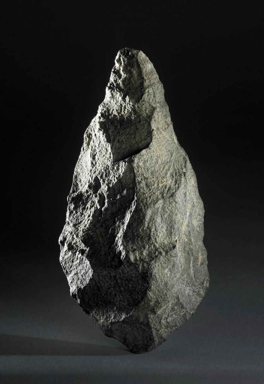 Handaxe made from dark brownish grey lava block. Pointed form with a regular, continuous edge.