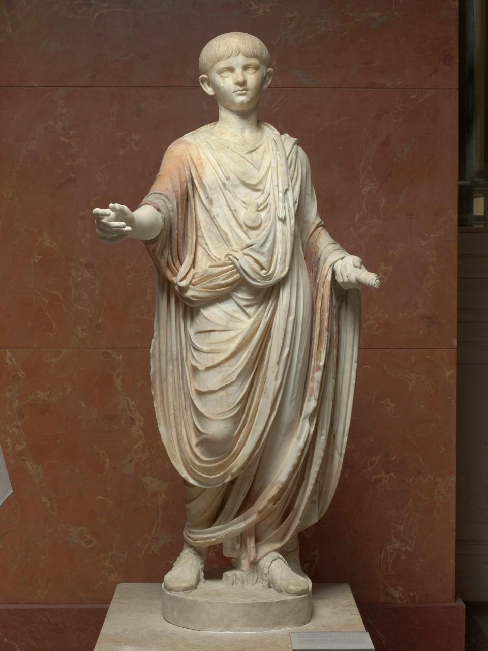 Statue of boy, draped in toga, one hand holding scroll