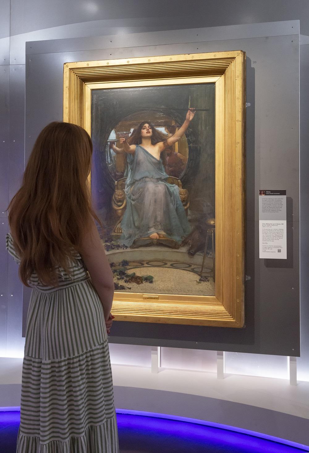 A woman standing in front of the painting of Circe in the Feminine power exhibition.