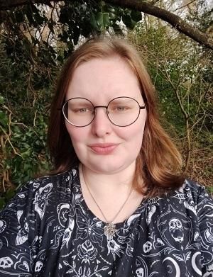 A photo of Jenny, who has caramel coloured hair and is wearing a black top with skulls.