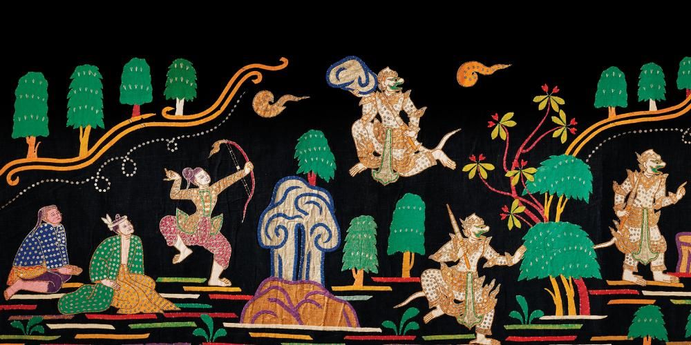 A black textile adorned with a colourful scene, including sitting figures surrounded by trees, a figure shooting an arrow towards the sky, and  Hanuman flying through the air carrying a rock, Hanuman (possibly carrying the Mountain of Herbs or Building the Bridge to Lanka), and Hanuman talking to a sage (with two hares below).