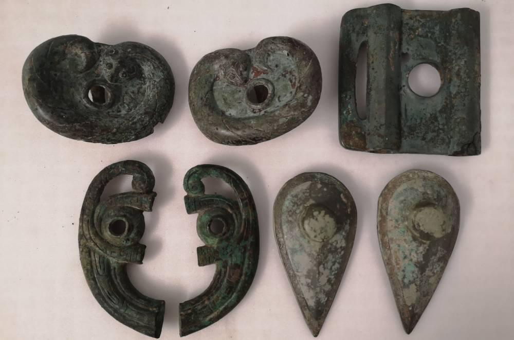 Six bronze cheekpieces arranged in two rows.