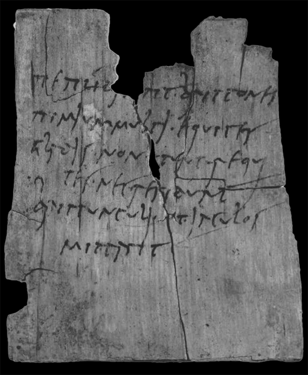 Black and white photograph of a fragment of a wooden tablet, covered in lines of cursive script in black ink