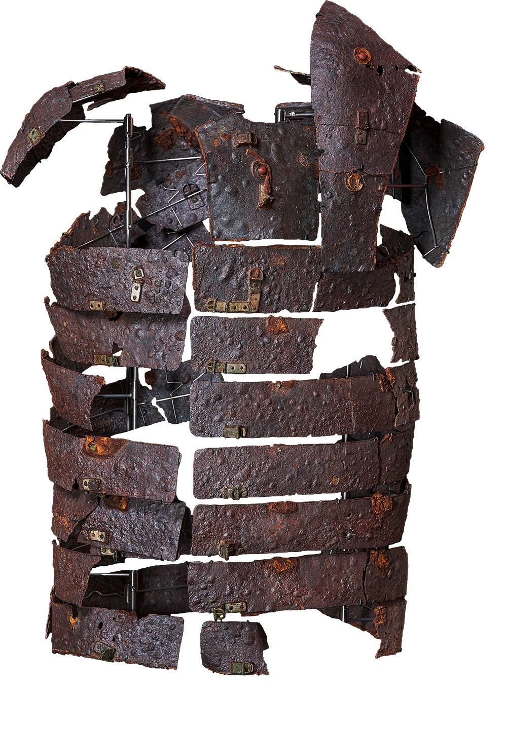 Bands of rusted metal armour are shaped around a construct to resemble a human torso. The metal is buckled and pockmarked