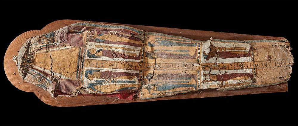 The base of a cartonnage coffin which has collapsed and is damaged in places. It is painted with figures and hieroglyphs