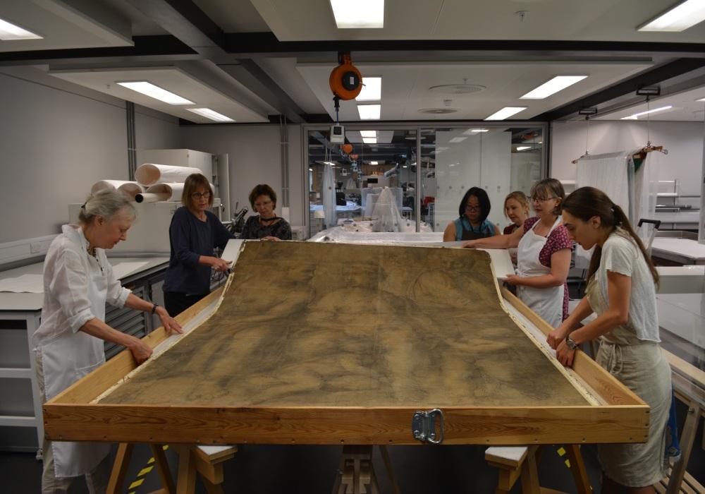 A group of conservators lifting the 'Epifania' from its mount.