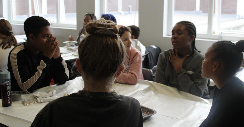 Group of young people sat at a table in discussion.